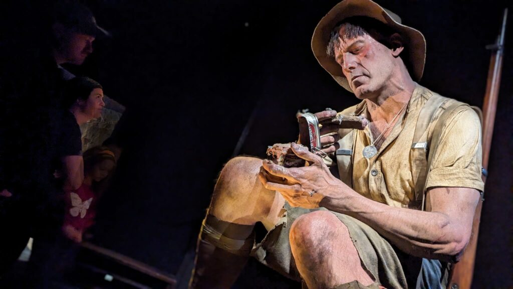 Visitors look at an exhibit of an ANZAC soldier opening a rancid can of meat