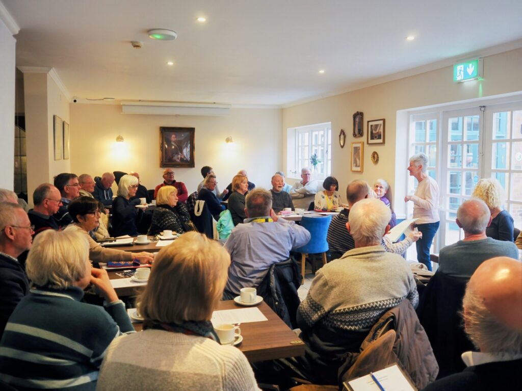 group of people sat at tables listening to a speaker