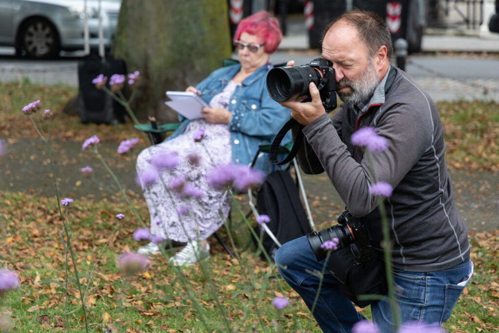 Photographer taking pictures of people sketching in a flower meadow