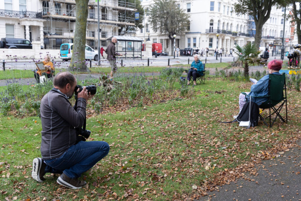 Photographer taking pictures of people sketching in a flower meadow